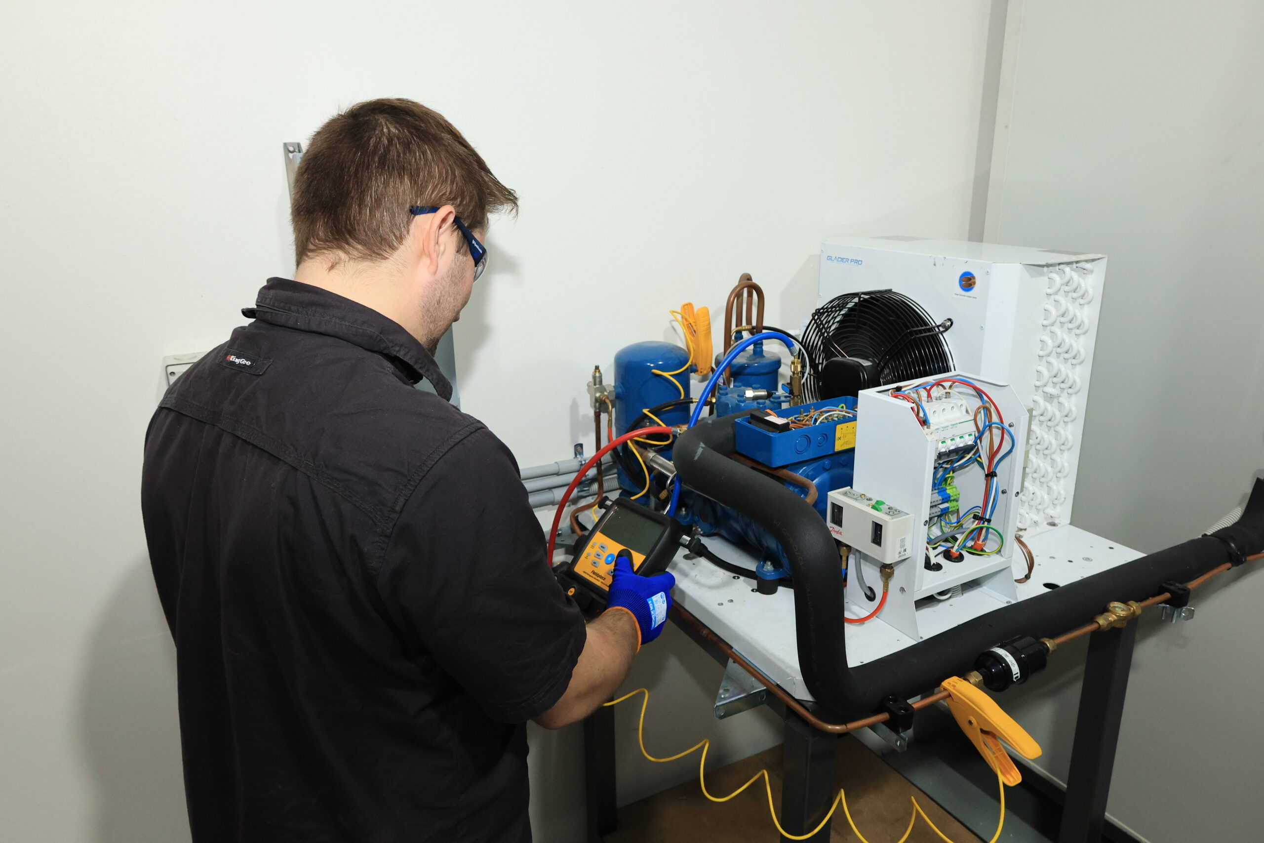 Man checking pressure measurements on refrigeration unit | Featured image for Certificate III in Refrigeration & Air Conditioning on Get Skilled Training